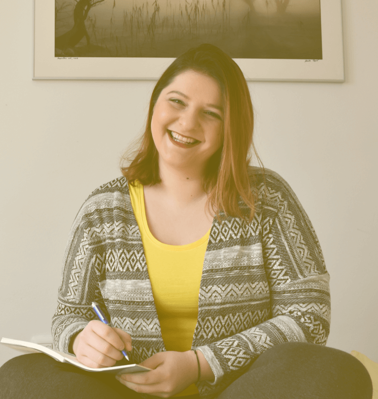 girl in yellow shirt laughing and holdin pen on paper